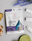 Scentral Zone Anti-Nausea Clip-On Diffuser in a purple and white pouch. Next to the pouch are three clip on diffusers. Surrounded by the product is items representing the key essential oil notes: ginger, lavender, peppermint.