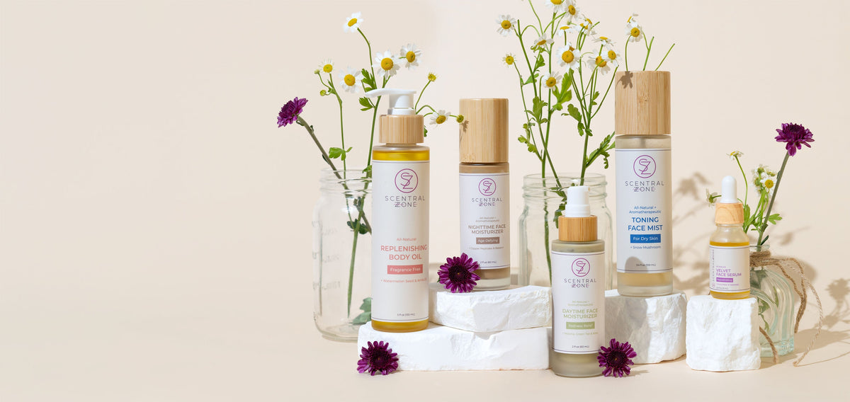 A variety of Scentral Zone's products including: Nourishing Body Oil, Redness Relief Moisturizer, Age-Defying Moisturizer, Toning Mist, and Velet Face Serum with small flowers scattered around the products.