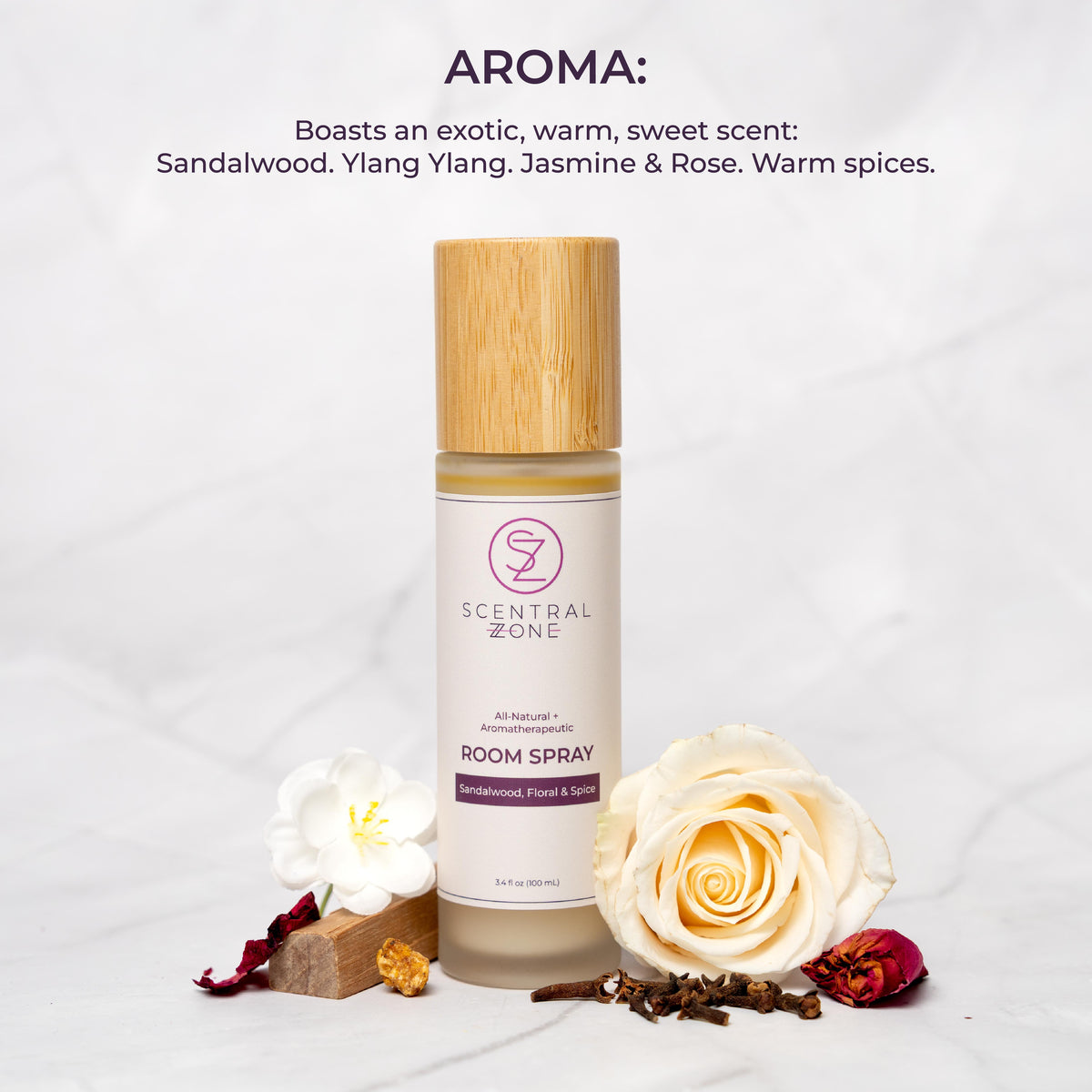 Scentral Zone Room Spray in scent Scandalwood, Floral, and Spice in a clear bottle with a bamboo wooden lid. Next to the bottle is a white rose, jasmine flower, and a small piece of wood. Text is displayed above the image explaining the aroma which is an exotic, warm, sweet scent. 